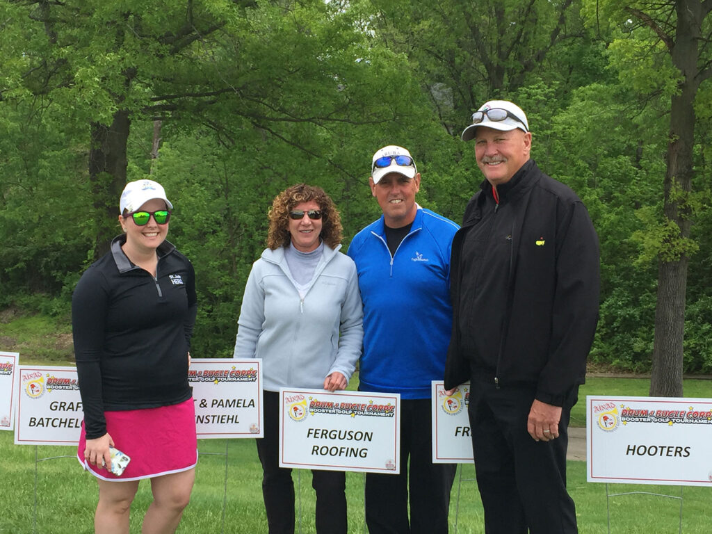 Ferguson team standing with signs at a golf tournament.