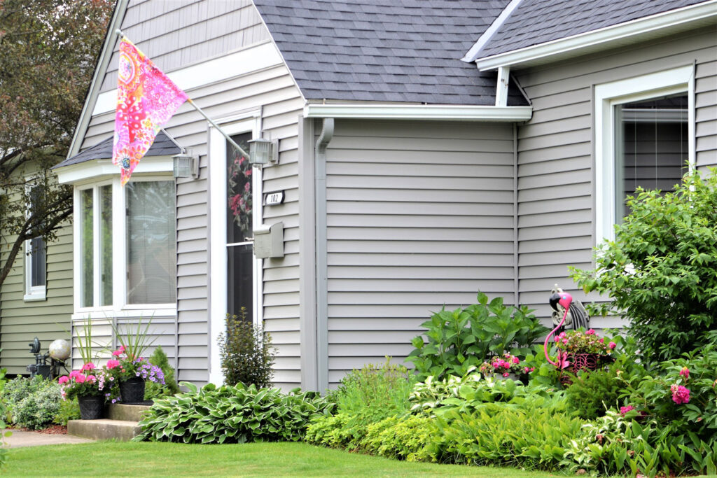 Exterior of residential home with a tidy garden and floral flag.