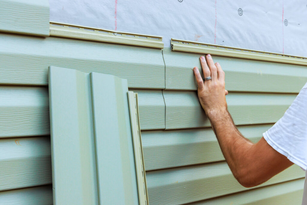 Homeowner installing new siding panels.